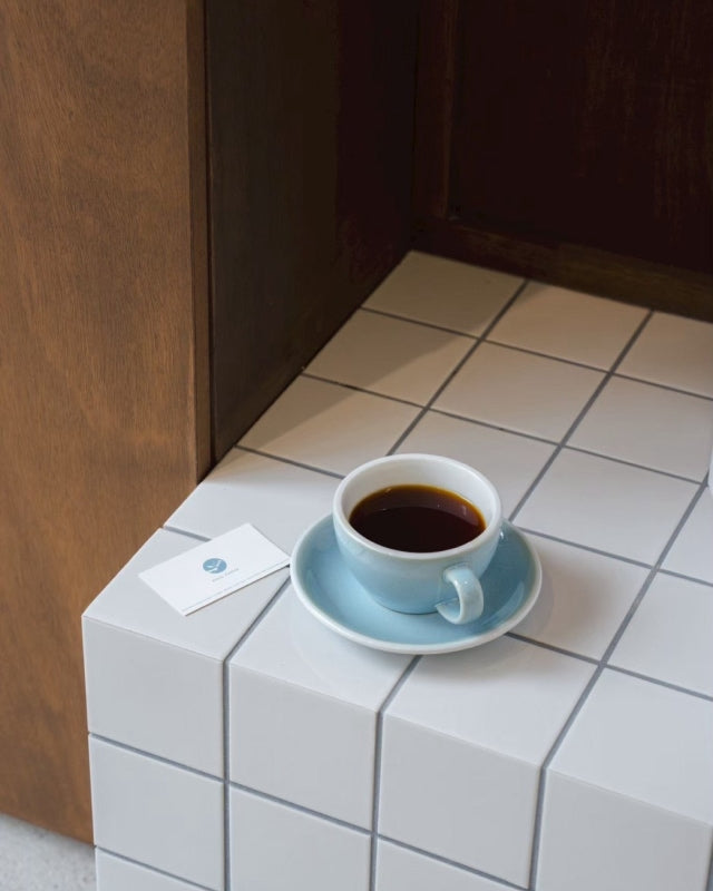 タイルのテーブルに置かれた青いカップのコーヒー